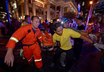 Thai rescue workers carry an injured person after a bomb exploded outside a religious shrine in central Bangkok late on August 17, 2015 killing at least 10 people and wounding scores more.  Body parts were scattered across the street after the explosion outside the Erawan Shrine in the downtown Chidlom district of the Thai capital.         AFP PHOTO / PORNCHAI KITTIWONGSAKUL