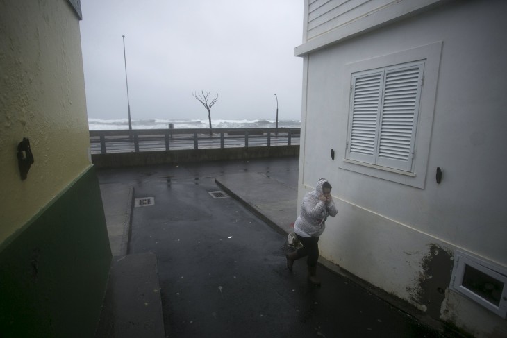 A woman takes cover from heavy rain and wind during the passage of hurricane Alex in Ponta Delgada, Azores, Portugal, January 15, 2016. REUTERS/Rui Soares  EDITORIAL USE ONLY. NO RESALES. NO ARCHIVE